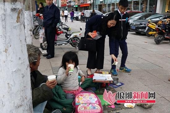 山东临沂一小女孩随父亲街头乞讨 寒风中裹棉被写作业(图) undefined